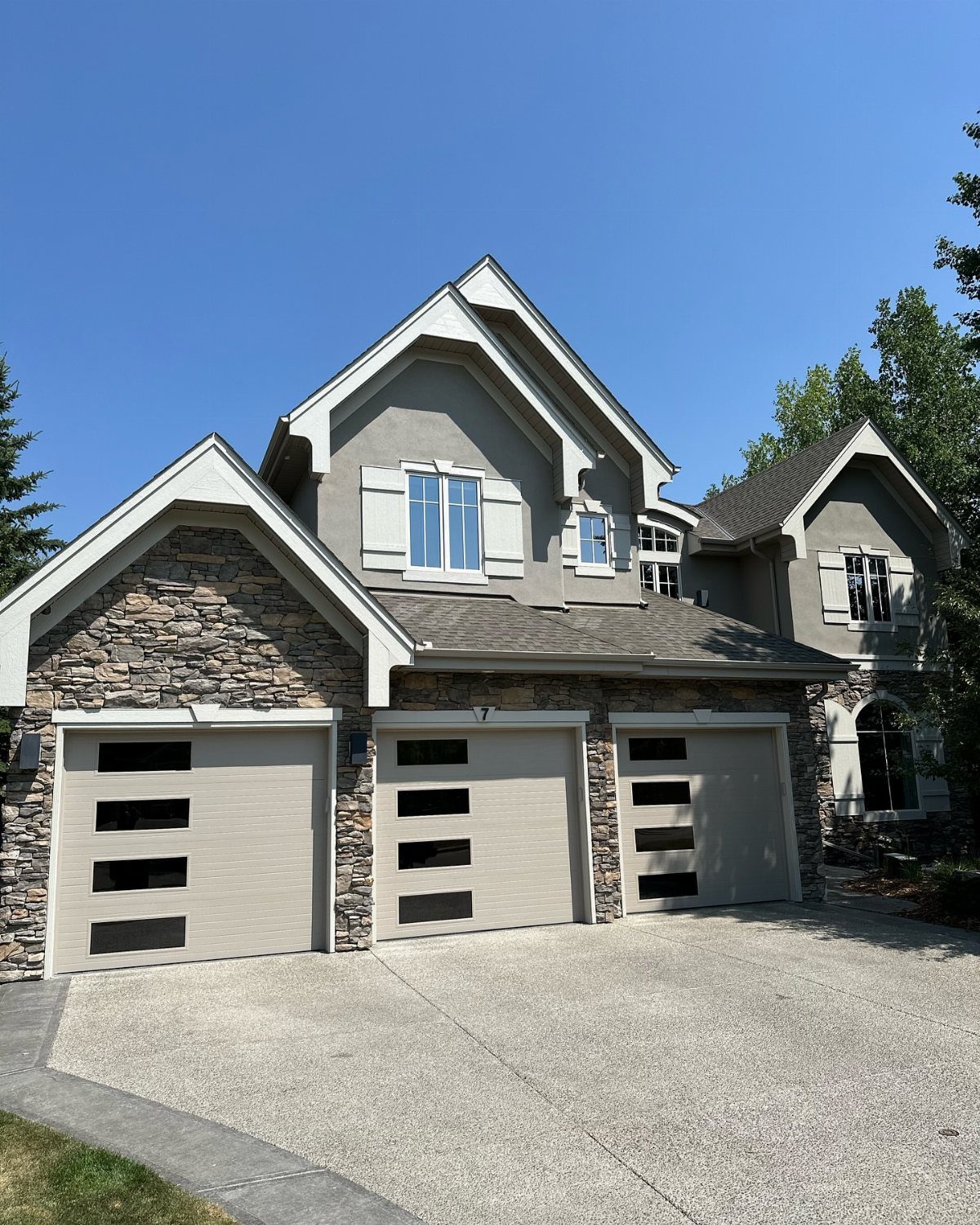 3 Car Garage Design: 8 Ideas for Style and Function 6 A modern house featuring a three-car garage with stone accents and a wide concrete driveway.