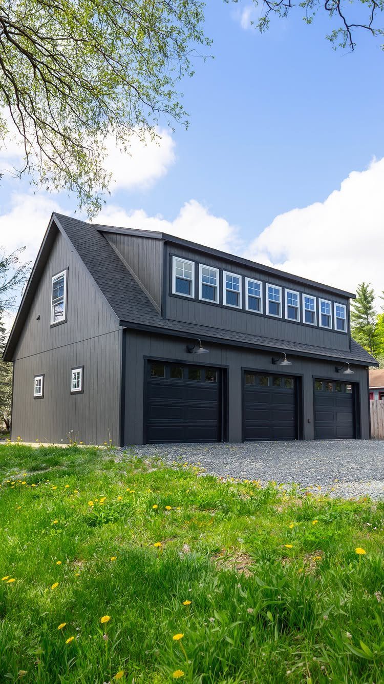 3 Car Garage Design: 8 Ideas for Style and Function 4 A large dark gray two-story garage with three black doors and white window frames.