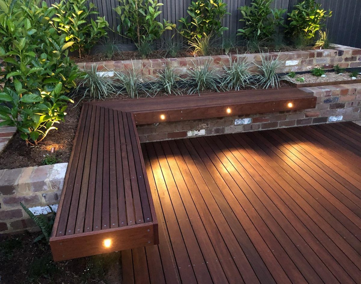 Built-in wooden L-shaped bench seating with integrated lights on a dark wood deck.