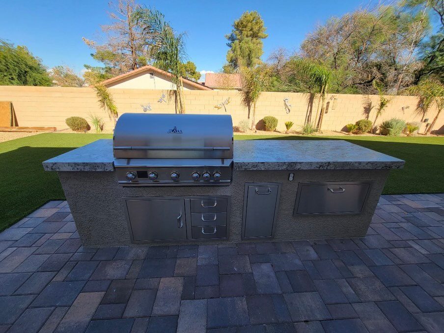 12 Backyard BBQ Ideas for Grill Area and Patio Layout 1 Stainless steel built-in grill with stone countertop on a paved patio area.
