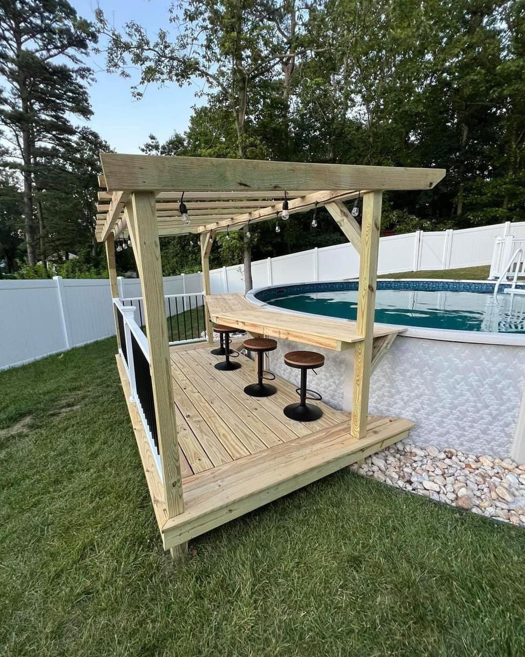 Backyard Pool Bar Ideas: 10 Upgrades for Summer Entertaining 9 Wooden poolside bar structure with stools and pergola next to an above-ground pool.