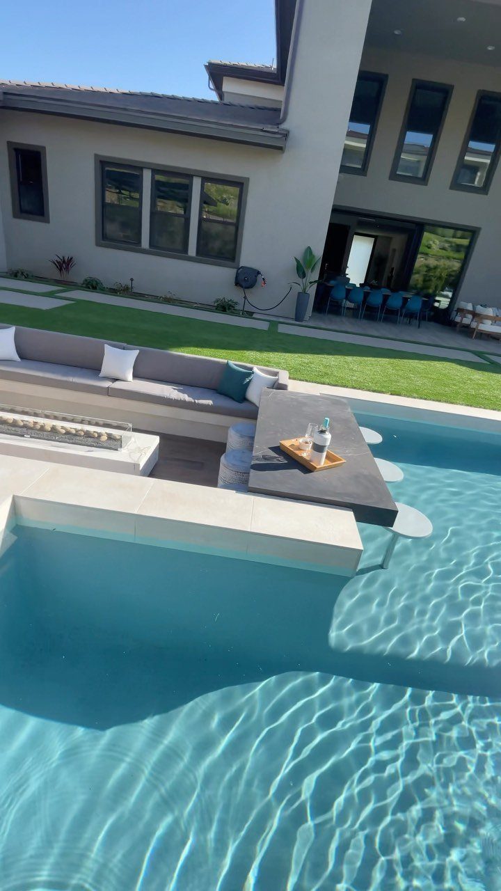 Backyard Pool Bar Ideas: 10 Upgrades for Summer Entertaining 8 Modern swimming pool with a sleek dark stone bar counter extending over the blue water.