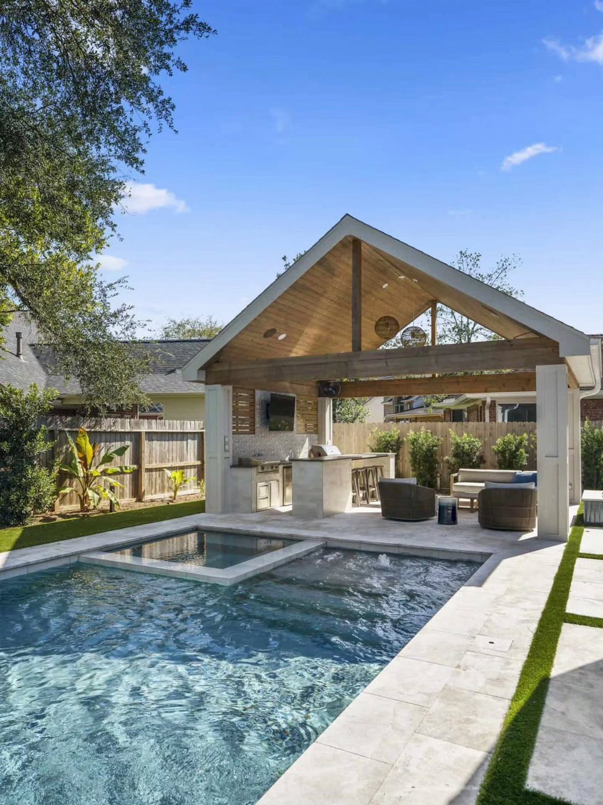 Backyard Pool Bar Ideas: 10 Upgrades for Summer Entertaining 5 Modern outdoor pavilion featuring a stone bar, kitchen area, and lounge seating next to a swimming pool.