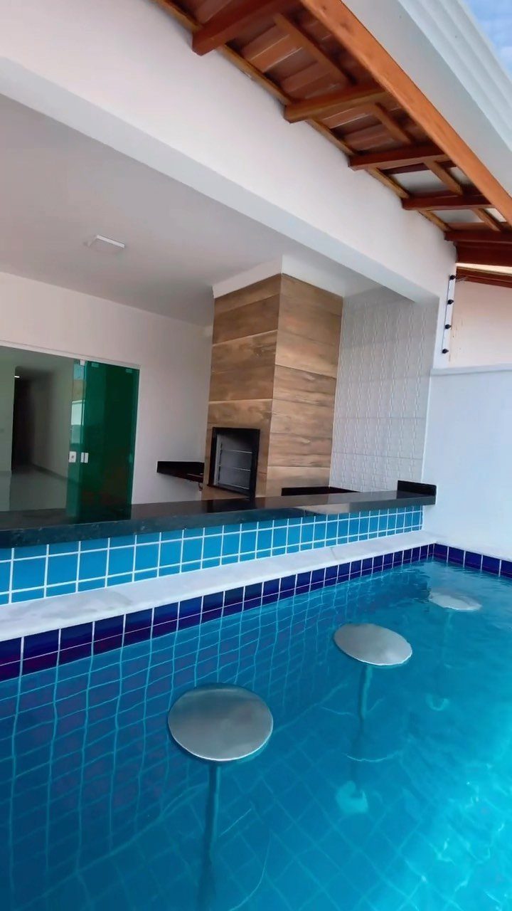 Backyard Pool Bar Ideas: 10 Upgrades for Summer Entertaining 4 Submerged silver stools sit in a blue swimming pool at a tiled swim-up bar.