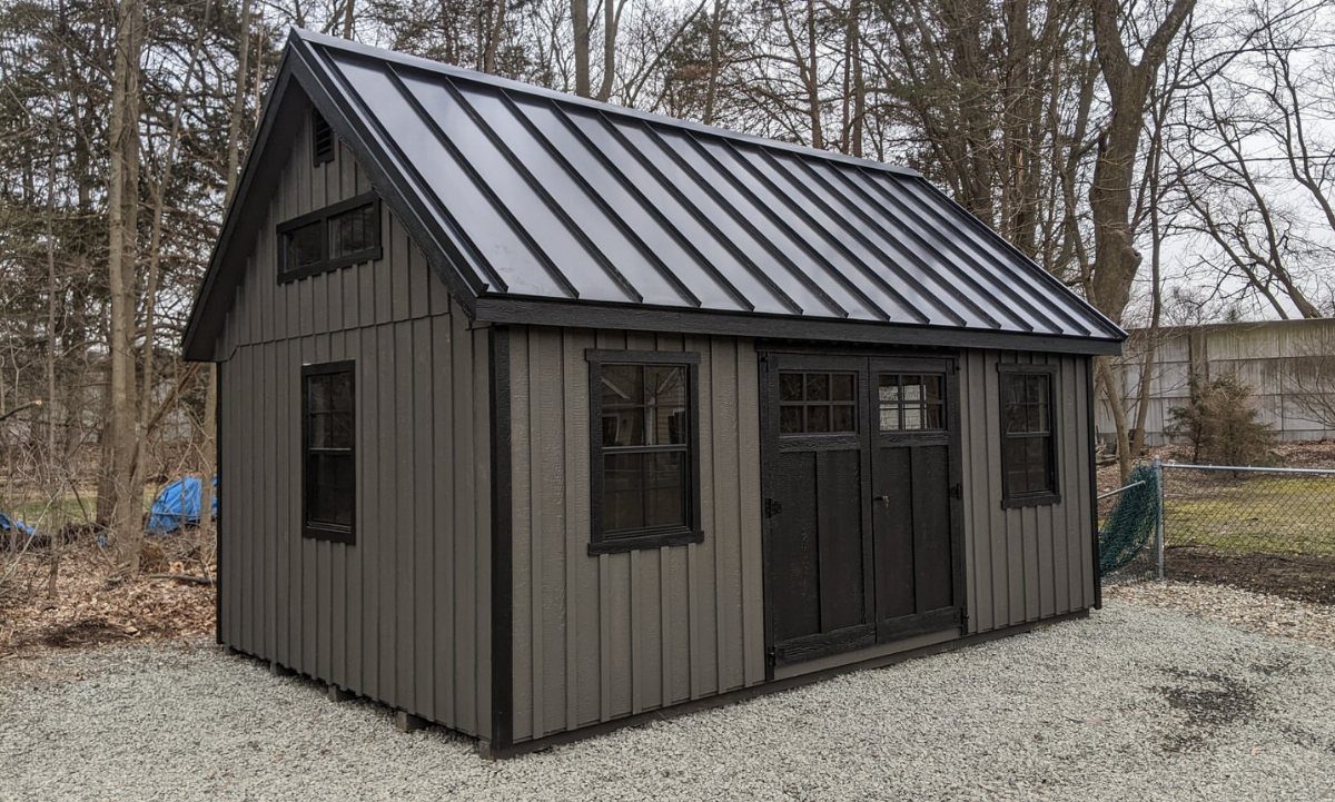 Board and Batten Shed: 5 Color Ideas That Work 4 A grey wooden shed with black board and batten siding and a black metal roof.