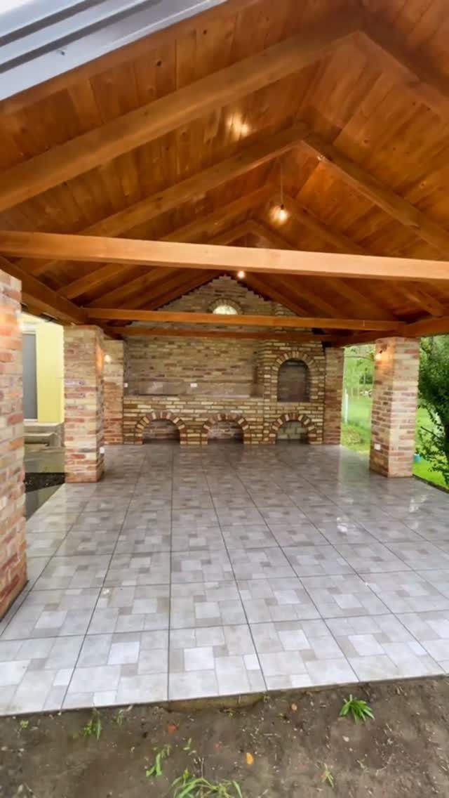 10 Brick BBQ Ideas: From Classic Pits to Pizza-Oven Combos 7 A large brick outdoor kitchen with multiple grill pits under a wooden pavilion roof.