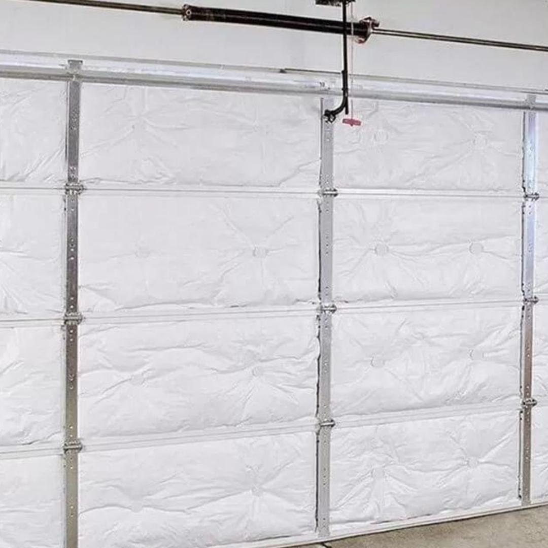 A white insulated sectional garage door with silver metal tracks and hardware installed.
