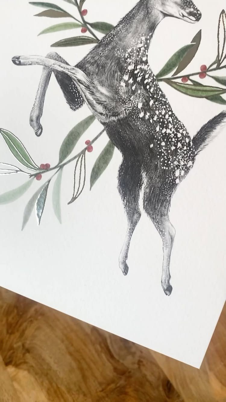 A black and white illustration of a spotted deer jumping through green leaves and red berries.