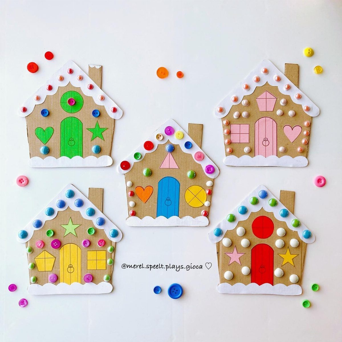 Five cardboard houses decorated with colorful buttons and paper shapes on a white background.