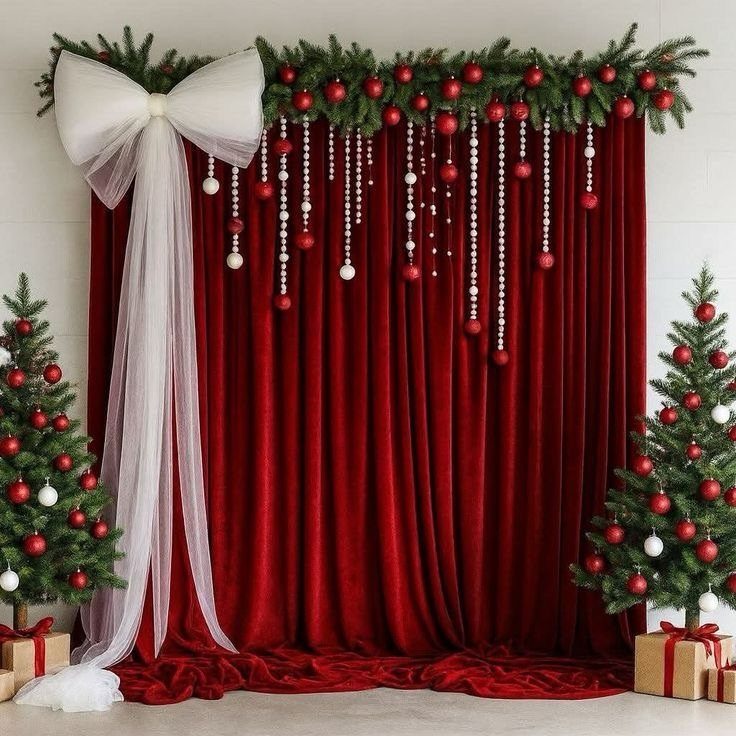 Red velvet backdrop decorated with pine garlands, ornaments, pearls, and a large white bow.