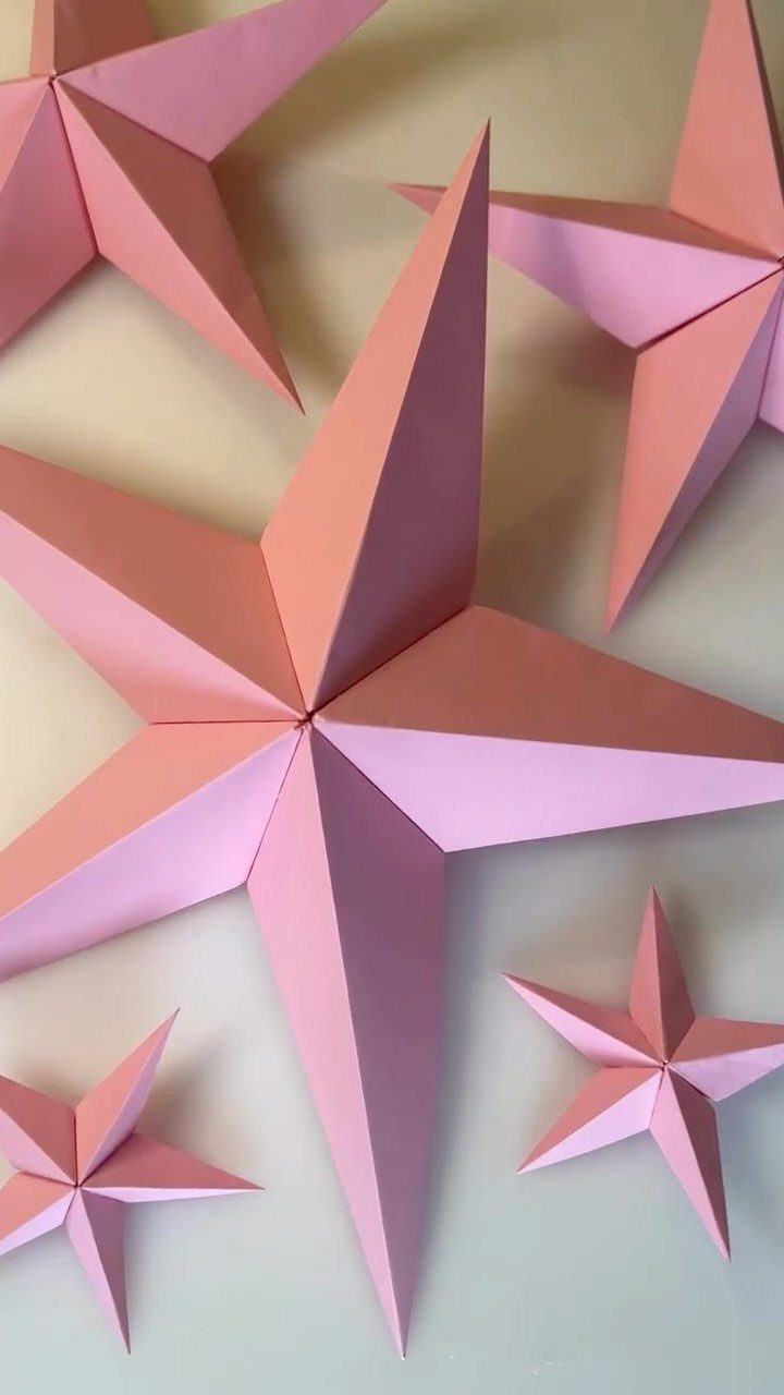 Pink and peach 3D paper star ornaments scattered on a light background.