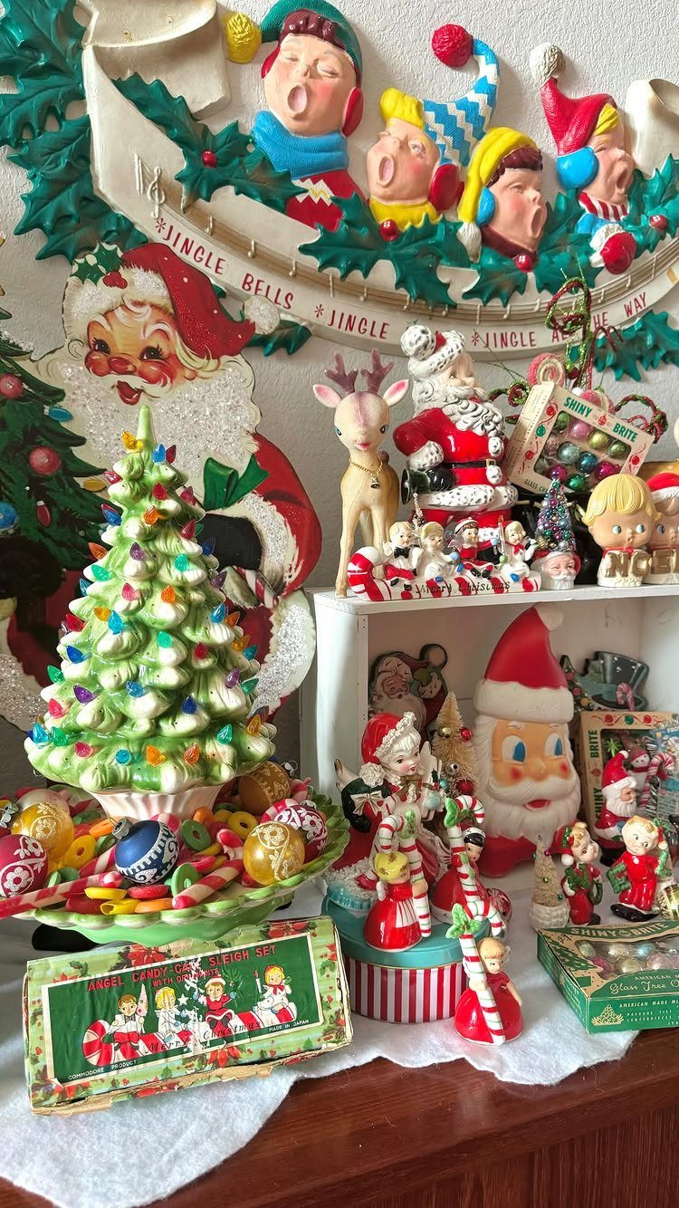 Vintage Christmas figurines including Santa Claus and reindeer arranged on a white shelf with festive decorations.