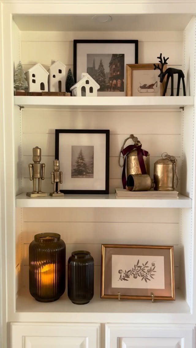 White shelves decorated with ceramic houses, framed pictures, nutcrackers, and amber glass candle holders.
