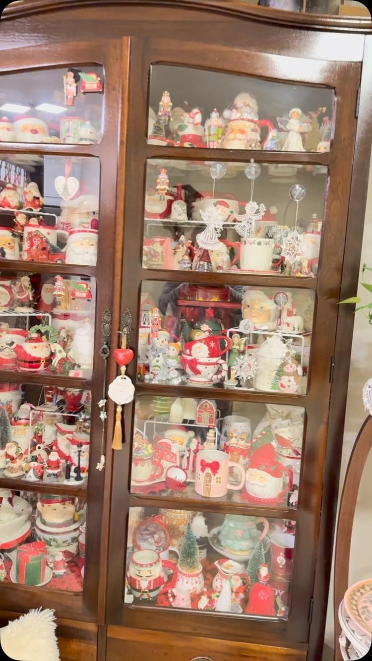 A wooden display cabinet filled with various vintage Christmas ornaments and festive ceramic figurines.