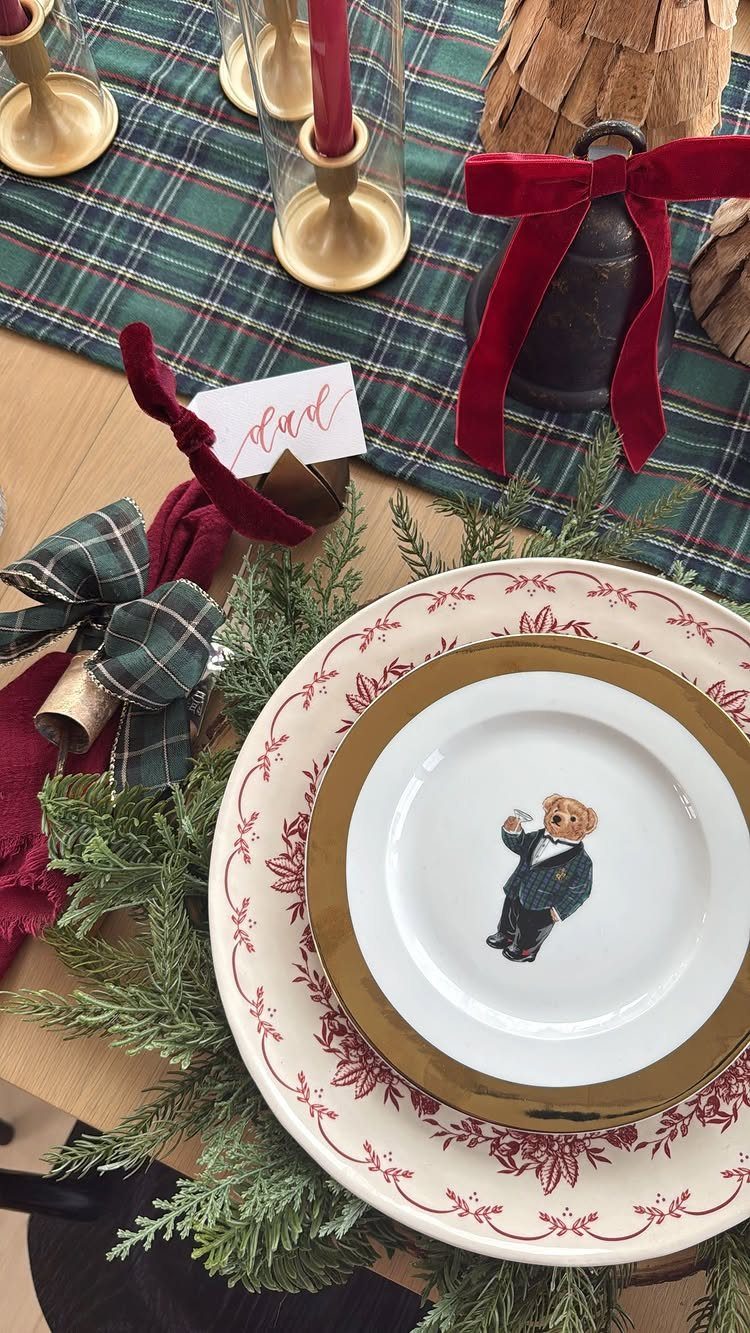 Layered vintage plates with red patterns and gold rims set on a bed of greenery.