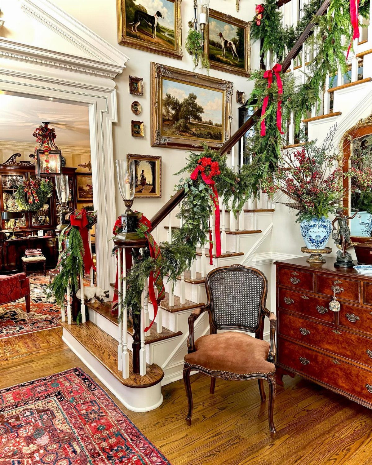 11 Classic Christmas Decor Ideas for Every Room in Your Home 3 Greenery garland with red bows draped along a wooden staircase railing in a classic room.