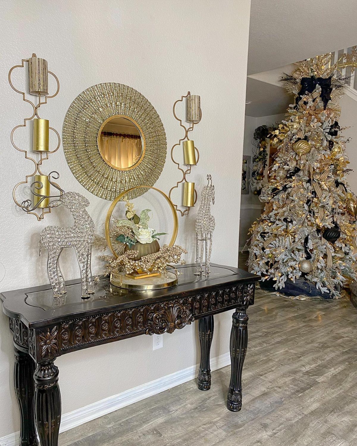 11 Classic Christmas Decor Ideas for Every Room in Your Home 11 Dark wood console table decorated with gold accents, a mirror, and a floral centerpiece.