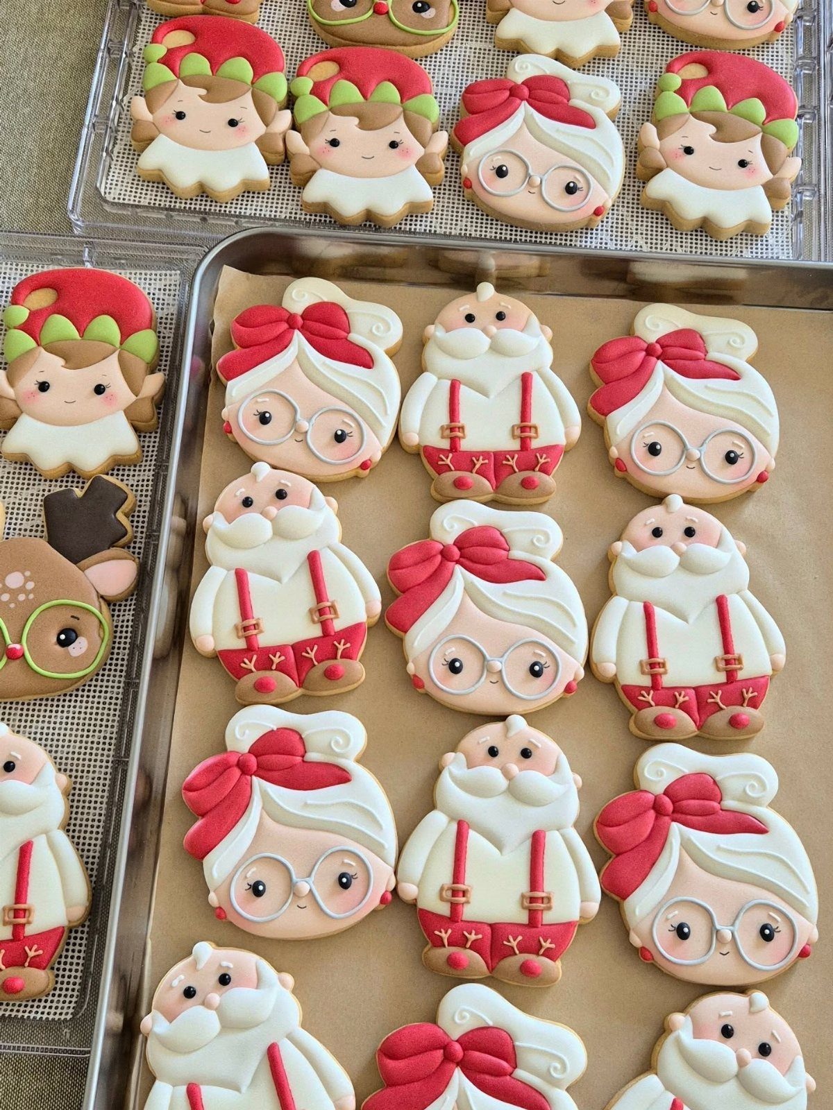 Decorated Christmas sugar cookies shaped like Santa Claus and elderly women with red bows and glasses.