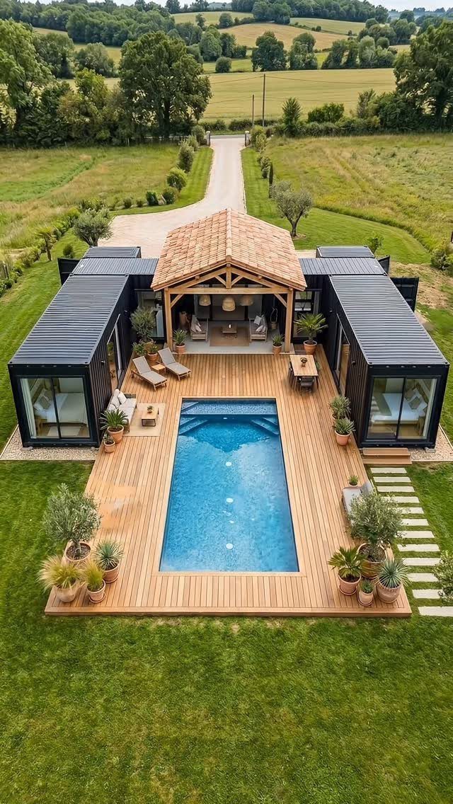 Aerial view of a wooden deck with a swimming pool and modern house in a countryside setting.