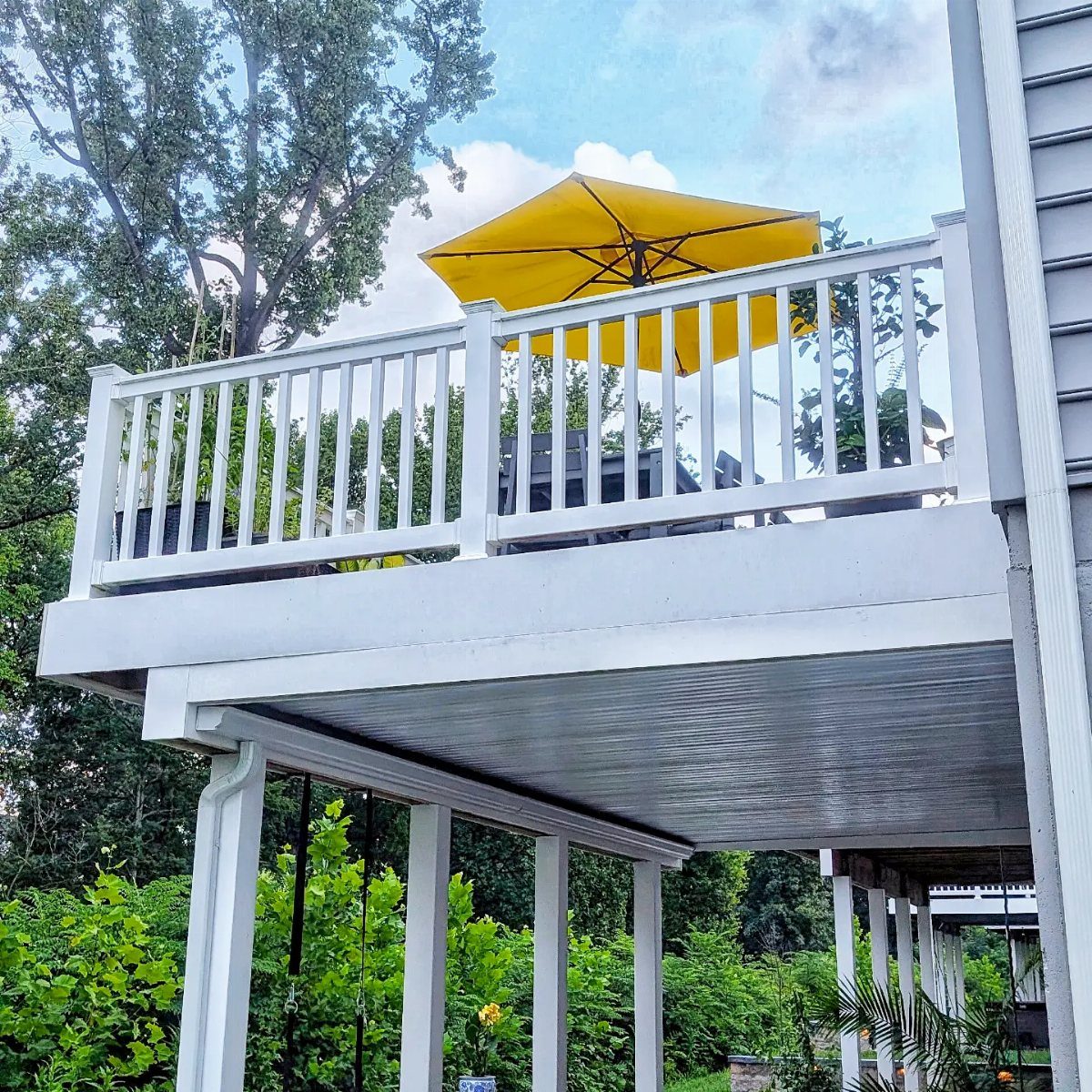 White deck with a yellow umbrella above a white gutter drainage system underneath.