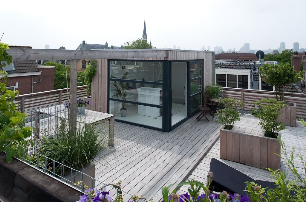 8 Deck with Roof Ideas for Every Backyard Layout 8 Wooden rooftop deck featuring glass-walled structure and several wooden planter boxes with green plants.
