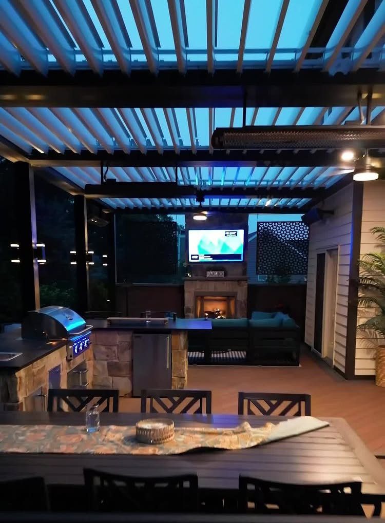 8 Deck with Roof Ideas for Every Backyard Layout 4 A modern outdoor patio featuring a dark metal louvered roof system and an outdoor kitchen.