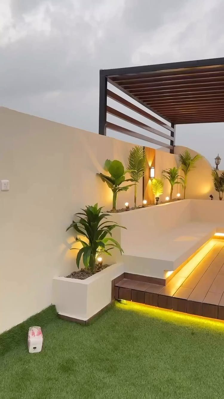 8 Deck with Roof Ideas for Every Backyard Layout 1 Modern outdoor terrace with a dark metal pergola, wooden deck, and tropical plants in white planters.