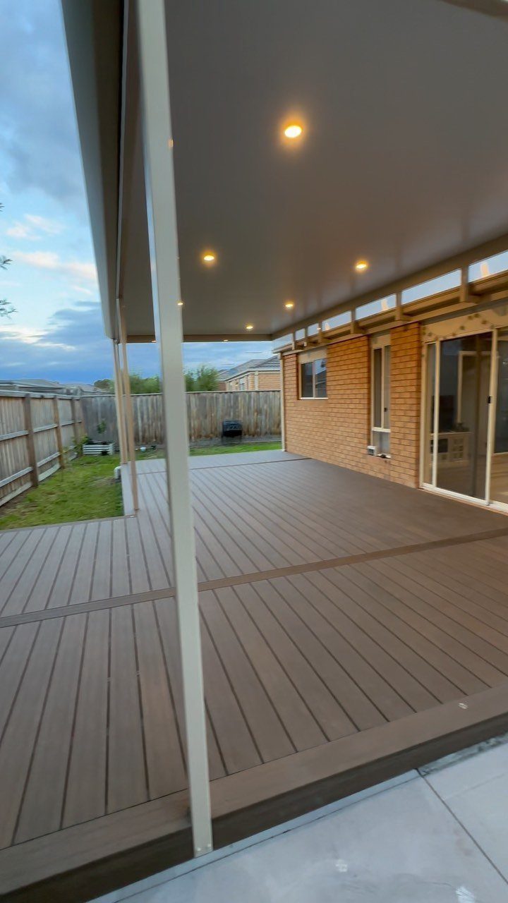 8 Deck with Roof Ideas for Every Backyard Layout 5 A wide wooden deck with a solid white roof and recessed lighting next to a brick house.