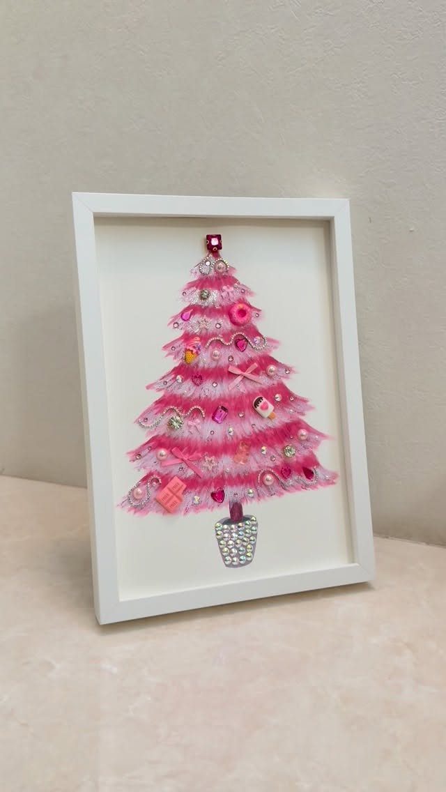 A pink textured Christmas tree craft displayed inside a white shadow box frame.