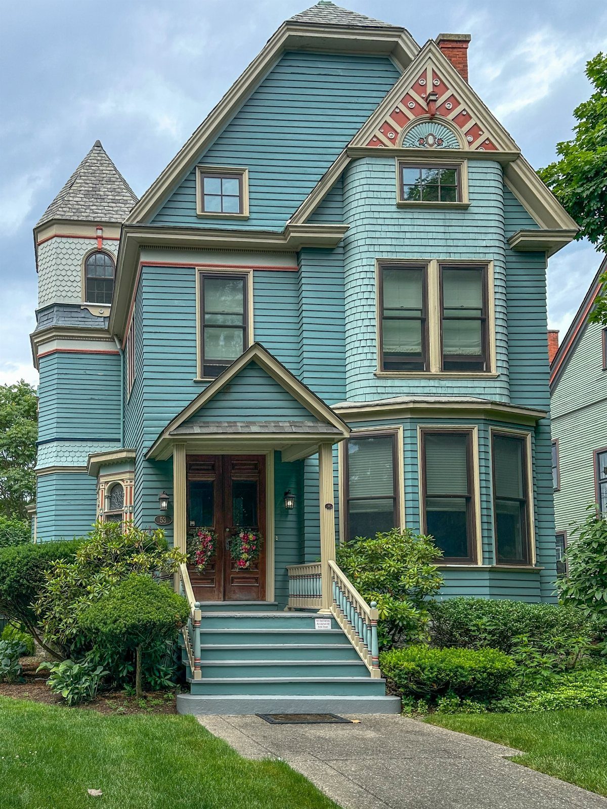 Exterior Color Ideas for 6 Home Styles 1 A multi-colored Victorian house with teal siding and red decorative trim surrounded by green foliage.