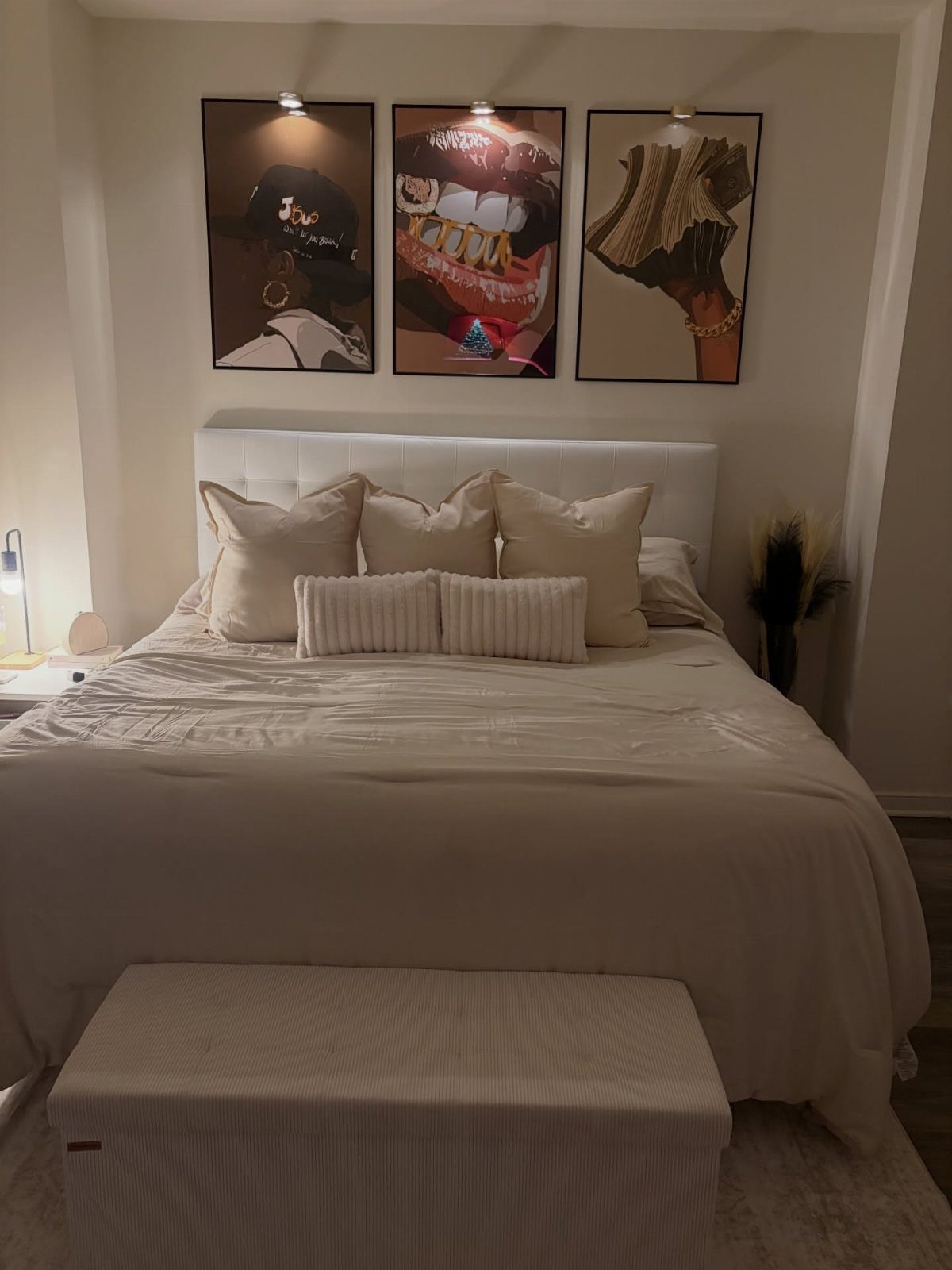 Garage to Bedroom Ideas: 7 Layouts Worth the Conversion Work 5 A white bed with decorative pillows sits beneath three large pieces of portrait artwork on a wall.
