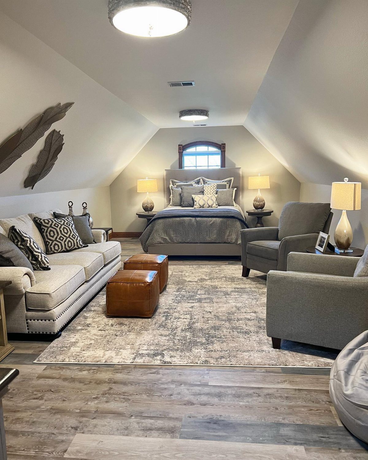 Garage to Bedroom Ideas: 7 Layouts Worth the Conversion Work 3 A cozy bedroom and living space with a bed, sofa, armchairs, and ottomans under sloped ceilings.