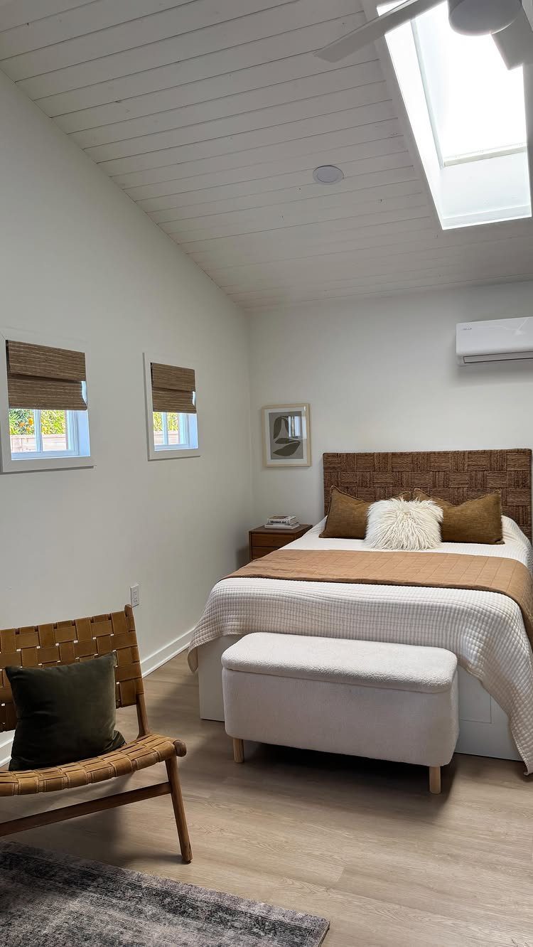 Garage to Bedroom Ideas: 7 Layouts Worth the Conversion Work 2 Bright bedroom featuring a large skylight on a white paneled ceiling and two small windows.