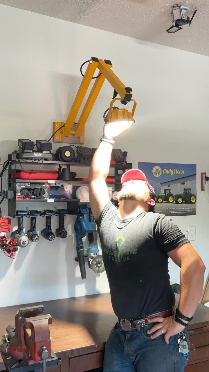 Garage Workbench Ideas: 11 Builds from IKEA Hacks to Heavy-Duty 5 A man reaches up to adjust a bright yellow articulated task lamp mounted on a garage wall.