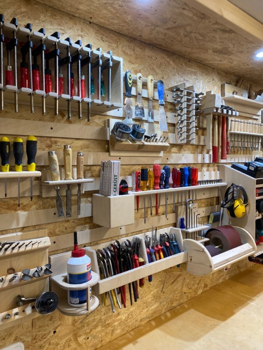 Garage Workbench Ideas: 11 Builds from IKEA Hacks to Heavy-Duty 4 Various hand tools and clamps organized in custom wooden holders on a workshop wall.