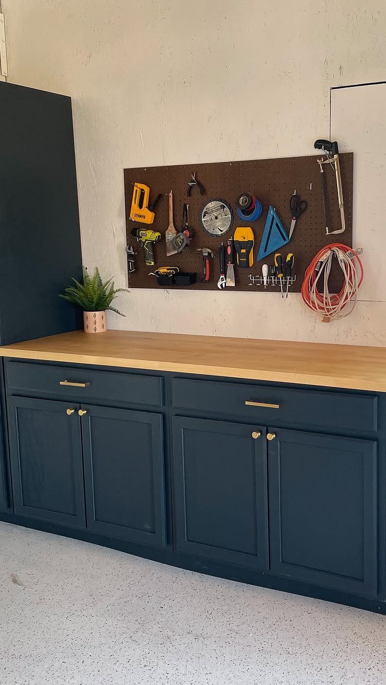 Garage Workbench Ideas: 11 Builds from IKEA Hacks to Heavy-Duty 1 Dark blue cabinets with a light wood countertop and a tool pegboard mounted on the wall.