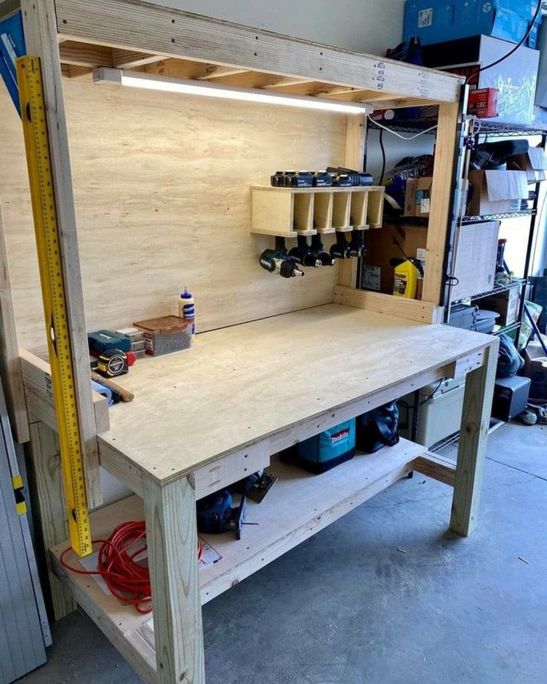 A sturdy wooden workbench with a plywood top, integrated lighting, and a drill organizer.
