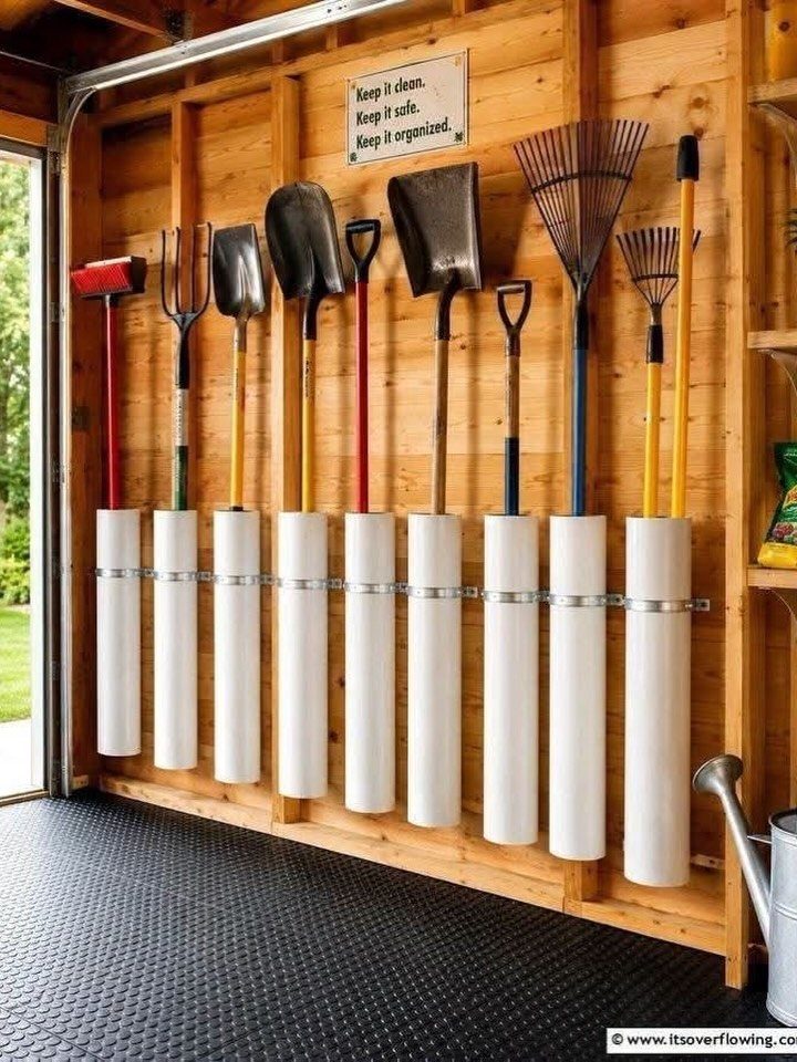 Garden tools hanging vertically on a wooden wall using white PVC pipe organizers.