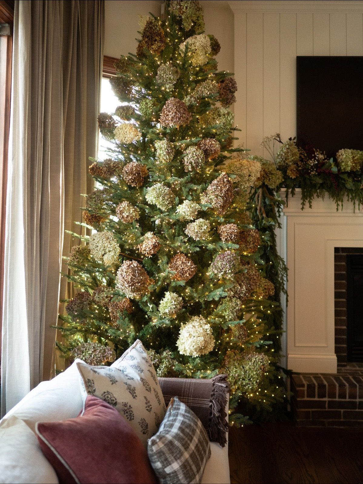 A Christmas tree decorated with large dried hydrangea blooms and warm glowing fairy lights.