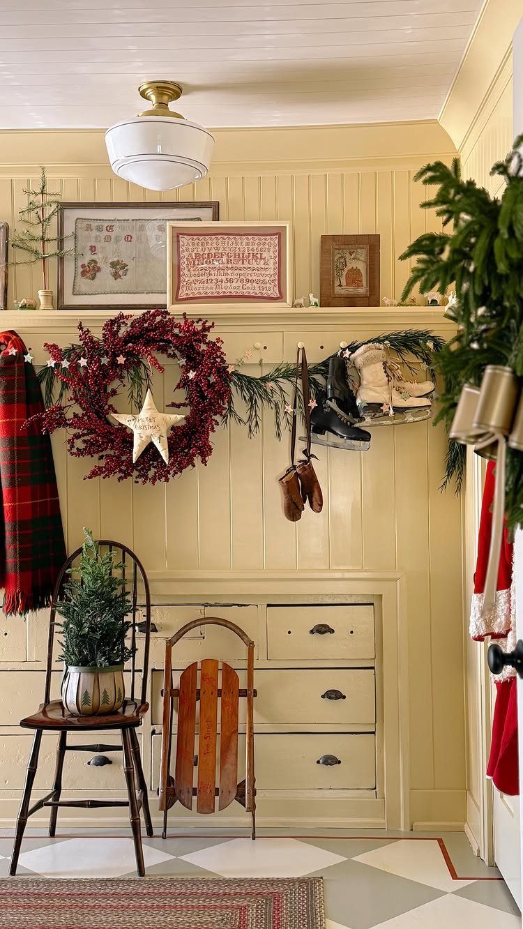 Festive entryway with a red wreath, evergreen garlands, a small pine tree, and a vintage wooden sled.