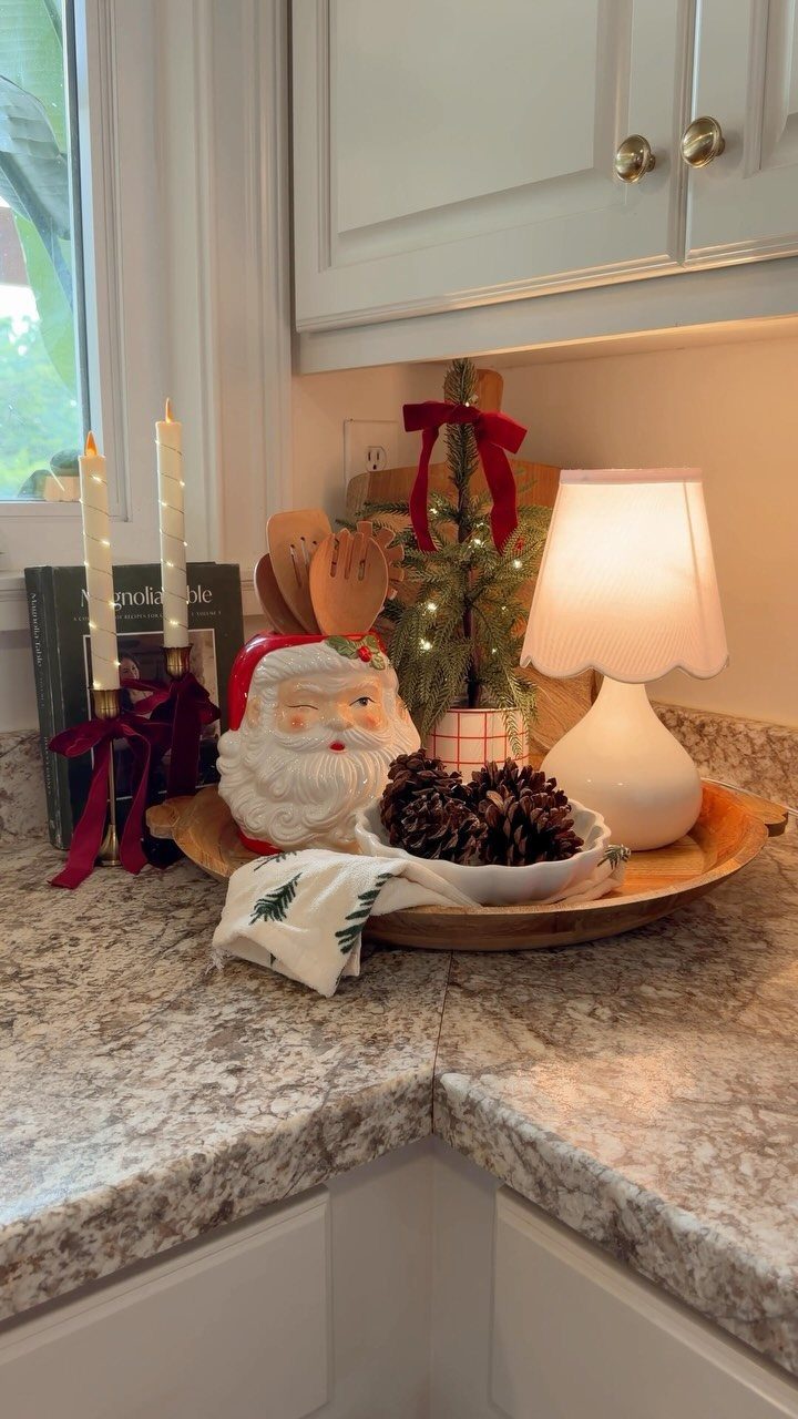 Christmas decorations including a small tree, Santa figurine, and pinecones on a kitchen counter.