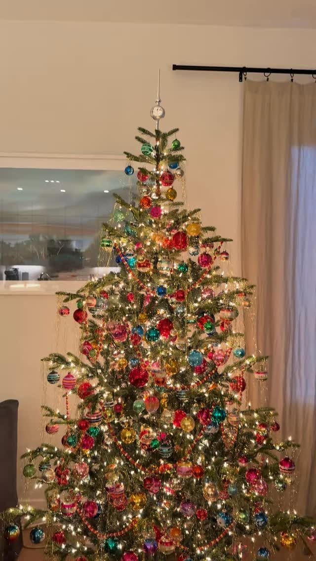 A decorated Christmas tree with colorful glass ornaments and warm glowing lights.