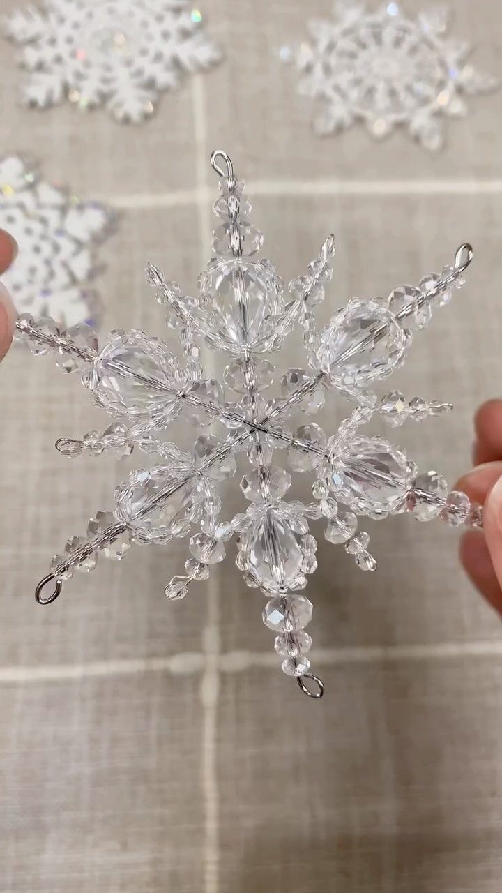Homemade Christmas Ornament Ideas: 8 Easy Projects 3 A person holding a clear crystal snowflake ornament against a light fabric background.