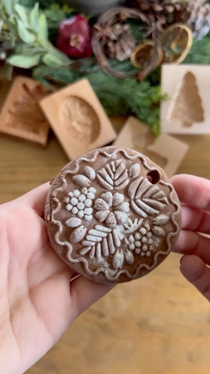 Homemade Christmas Ornament Ideas: 8 Easy Projects 1 Hands holding a round, patterned salt dough ornament with floral designs against a festive background.