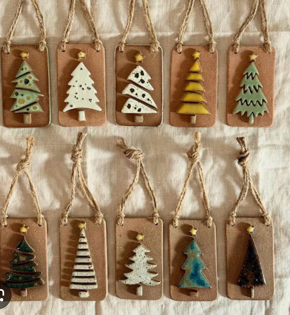 Ten handmade clay Christmas tree ornaments hanging from twine on a neutral fabric background.