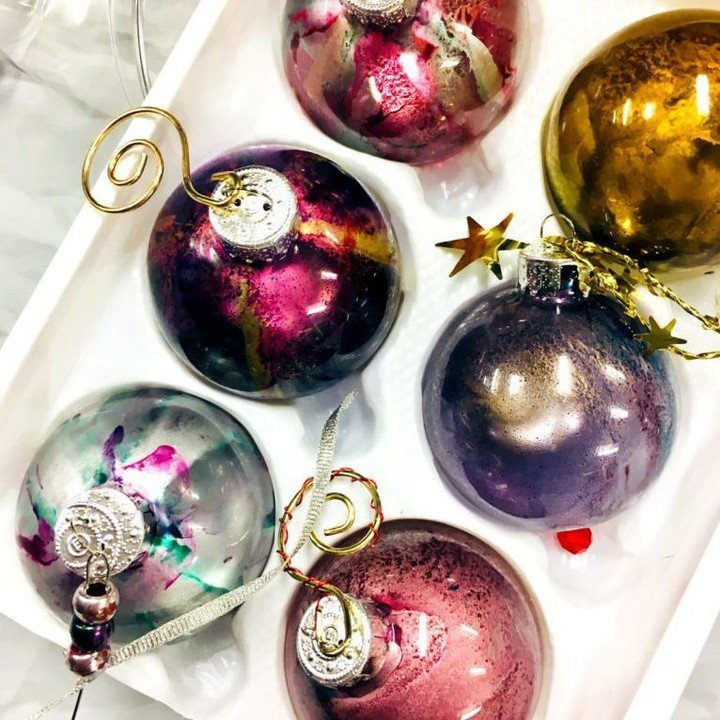 Marbled alcohol ink Christmas ornaments in various colors resting inside a white tray.