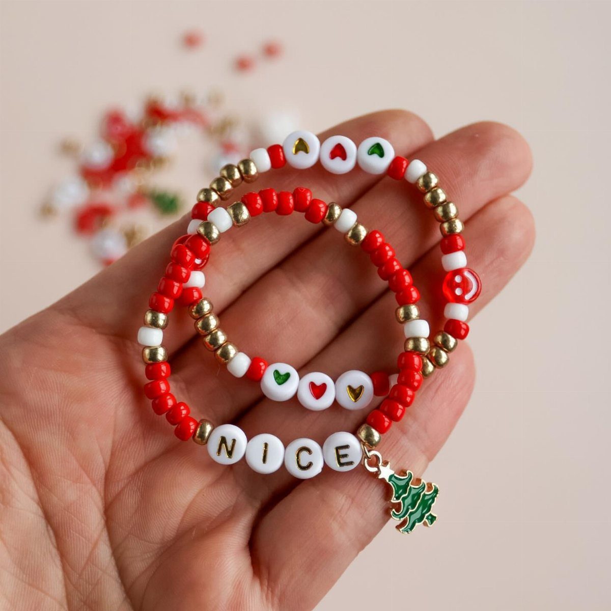 Two beaded Christmas friendship bracelets with red, white, and gold beads held in a hand.