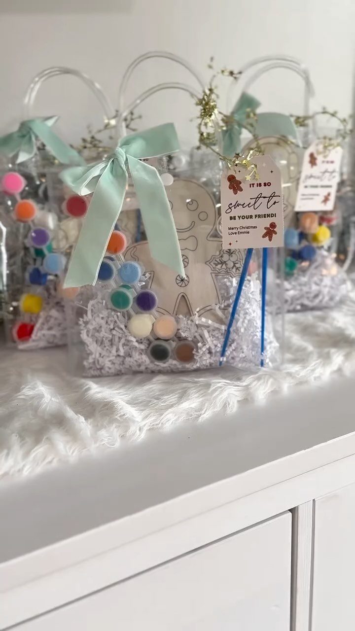 Clear gift bags filled with paint pots and wooden gingerbread man craft supplies.