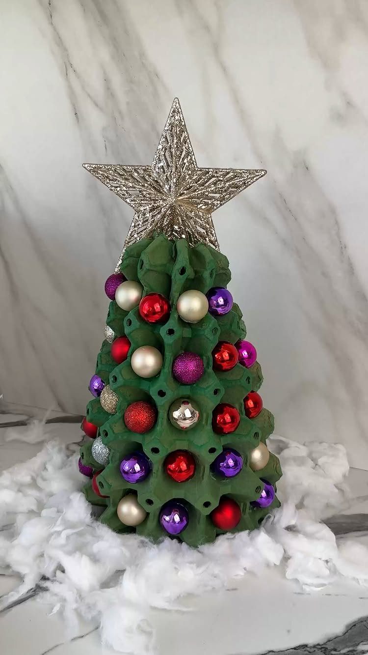 A green egg carton Christmas tree decorated with colorful ornaments and a silver star topper.