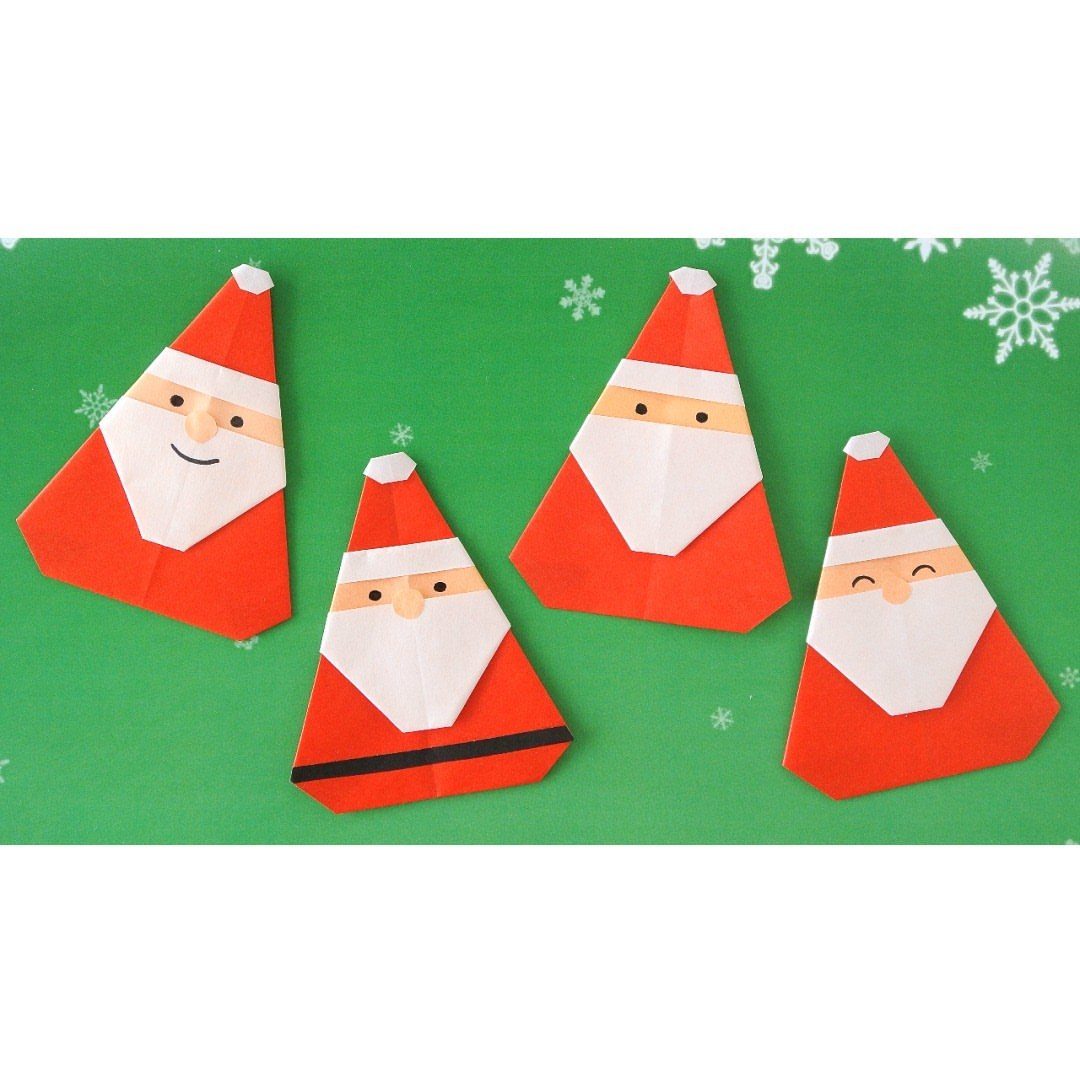 Four red and white origami Santas resting on a green snowflake patterned background.